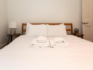 dos toallas están sentadas en una cama blanca en Pass the Keys Modern Condo in Brixton, en Londres