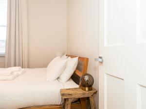 a bedroom with a bed with white sheets and a wooden table at Pass the Keys Modern Condo in Brixton in London