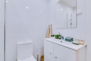 La salle de bains blanche est pourvue d'un lavabo et d'un miroir. dans l'établissement Faro: Casa Trevo com terraço BBQ, à Faro