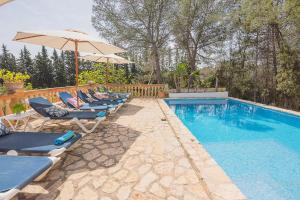 uma fila de cadeiras e um guarda-sol junto a uma piscina em Ca na Tinta em Algaida