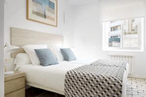 1 dormitorio blanco con 1 cama grande con almohadas azules en Apartamento Aizkorri by SanSe Holidays, en Añorga-Lugariz
