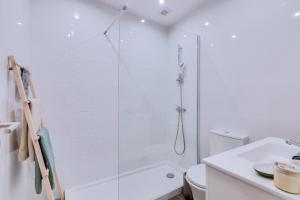 La salle de bains blanche est pourvue d'une douche et de toilettes. dans l'établissement Faro: Casa Trevo com terraço BBQ, à Faro