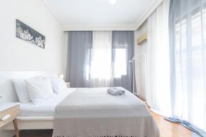 a white bedroom with a bed and a window at Houseloft Ambiance Park in Thessaloniki