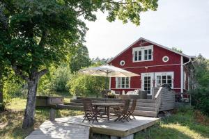 a red barn with a table and chairs and an umbrella at Villa Funkis Strömmen - Gorgeous Villa by the sea! in Nauvo