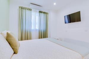 a white bedroom with a bed and a television at Faro: Casa Trevo com terraço BBQ in Faro