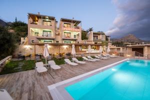 a hotel with a swimming pool and lounge chairs at Portela Suites Kastri in Keratokampos