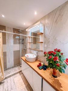 a bathroom with a sink and red flowers on a counter at THEA STUDIOS Eurostina in Pírgos