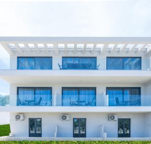 Dionisos Luxury Suites في تسيليفي: مبنى أبيض مع كراسي زرقاء على الشرفة