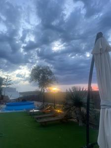 a view of a pool with benches and an umbrella at La Gardana, casa de campo mallorquina in Porreres