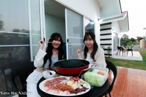 two women sitting at a table with a plate of food at บ้านสวนมะม่วงรีสอร์ท in Ban Klang +31 photos