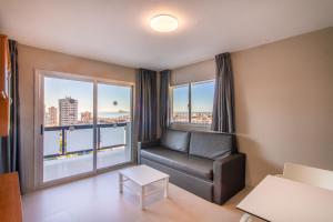 a living room with a couch and a large window at Apartamentos Michel Angelo Benidorm in Benidorm