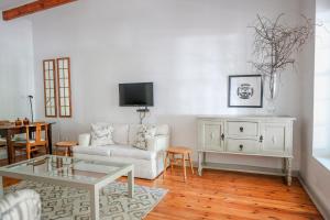 a living room with a white couch and a tv at Cottage 1 at River Bend in Graaff-Reinet