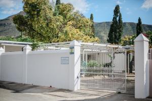 a white fence with trees and mountains in the background at Cottage 1 at River Bend in Graaff-Reinet