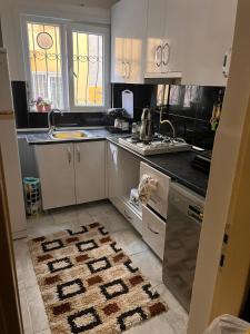 a kitchen with white cabinets and a rug on the floor at kadıköy modada denize yakın oda in Istanbul