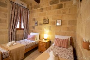 a bedroom with two beds and a window at Ta' Salvu Holiday Home in Xagħra