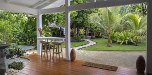 a porch with a table and chairs and a garden at Papaya Villa in Port Vila