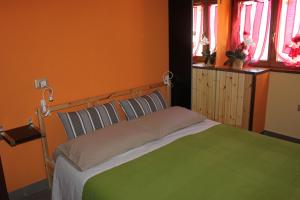 a bed in a room with orange walls and windows at La Madonnina in Villa di Tirano