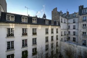 a white building with a black roof and buildings at Perfect Parisian Apartment LeMarais for you! in Paris