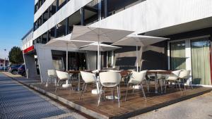 un grupo de mesas y sillas con sombrillas en un edificio en AMEDIA Hotel, en Noventa di Piave