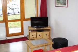 ein Wohnzimmer mit einem TV auf einem Holztisch in der Unterkunft Residence Le Hameau du Sauget - maeva Home in Les Coches