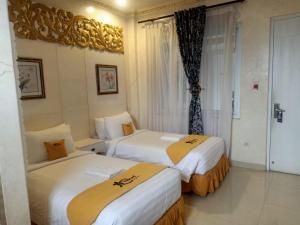una camera d'albergo con due letti e una finestra di MY HOME @BALI HOTEL BY CONARY a Kuta