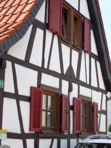 uma casa de enxaimel com janelas com persianas vermelhas em Ferienhaus Pfalzklause em Billigheim-Ingenheim