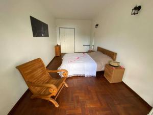 ein Schlafzimmer mit einem Bett und einem Holzstuhl in der Unterkunft Villa Trésor Péi - Mon îlet in La Possession