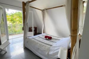 a bedroom with a canopy bed and a balcony at Villa Trésor Péi - Mon îlet in La Possession