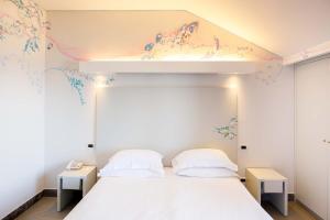 ソレントにあるアート ホテル グラン パラディソの白いベッド1台、壁に花が描かれたベッドルーム1室