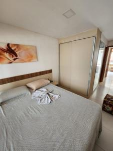 a bedroom with a white bed with a painting on the wall at Village Mediterrâneo in Cabo de Santo Agostinho