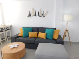sala de estar con sofá azul y almohadas coloridas en PERLA Penthouse, en Gran Tarajal