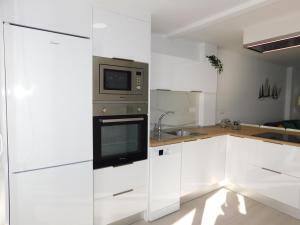 cocina con armarios blancos y microondas en PERLA Penthouse, en Gran Tarajal