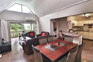 a living room with a wooden table and a kitchen at 52 The Bridge Apartment in St Lucia