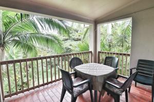 a porch with a table and chairs and a palm tree at 52 The Bridge Apartment in St Lucia