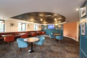 Knowsley Inn & Lounge formally Holiday Inn Express في نوزلي: مطعم بطاولات وكراسي وبار