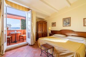 a bedroom with a bed and a balcony with a table at Hotel Mediterraneo in Syracuse