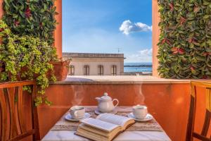 - une table avec une théière et des livres sur le balcon dans l'établissement Hotel Mediterraneo, à Syracuse