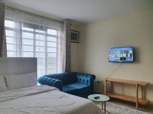 - une chambre avec un canapé bleu et une télévision dans l'établissement Regional Homes, à Syokimau