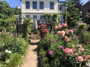 a garden in front of a white house with flowers at Ferienwohnung Villa Barbara auf der sächsischen Weinroute in Radebeul