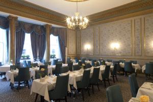 a dining room with tables and chairs and a chandelier at Gem Strathmore Hotel in London