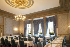 una sala da pranzo con tavoli, sedie e lampadario a braccio di Gem Strathmore Hotel a Londra