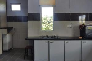 日得拉的住宿－Azhar Homestay，厨房配有白色橱柜和窗户。