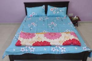 a bed with a blue comforter with flowers on it at Azhar Homestay in Jitra