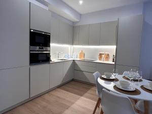 una cocina con armarios blancos y una mesa con sillas blancas. en Churruca apartment with terrace, en San Sebastián