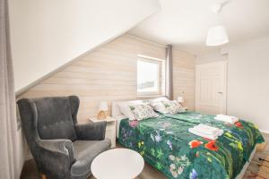 ein kleines Schlafzimmer mit einem Bett und einem Stuhl in der Unterkunft Bliżej Nieba in Skrzydlna
