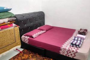 Bett in einem Zimmer mit einer lila Tagesdecke und einem Kopfteil in der Unterkunft D'Haja 5 KLIA Sepang with Free Wi-Fi & 3 Airconds in Banting