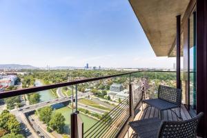 a balcony with two chairs and a view of a river at Design apartment with amazing view over Vienna in Vienna
