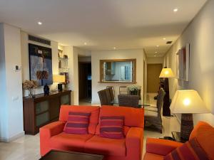 a living room with an orange couch with purple pillows at ALCAZABA beach in Estepona