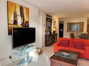 a living room with a red couch and a flat screen tv at ALCAZABA beach in Estepona