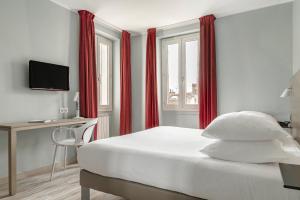 a bedroom with a bed with red curtains and a desk at Grand Hôtel Dauphiné, Boutique Hôtel & Suites in Toulon